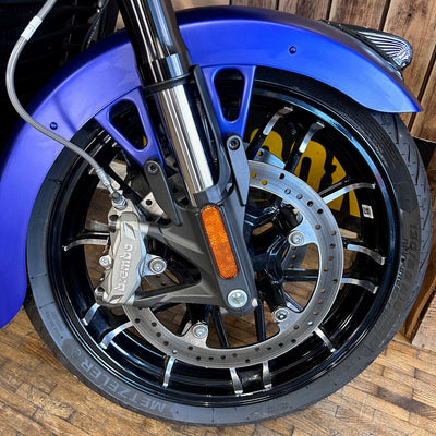 Close-up of a motorcycle wheel with blue fender on a wooden surface