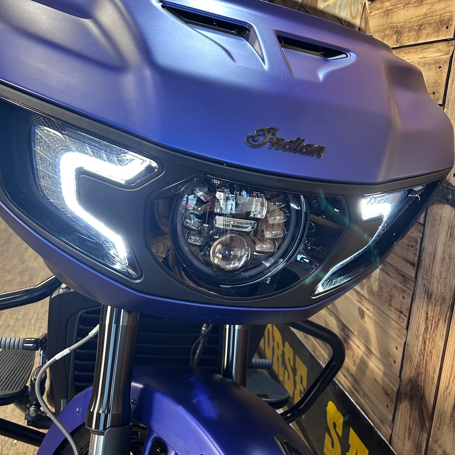 Close-up of a blue motorcycle with 'Indian' branding against a wooden background