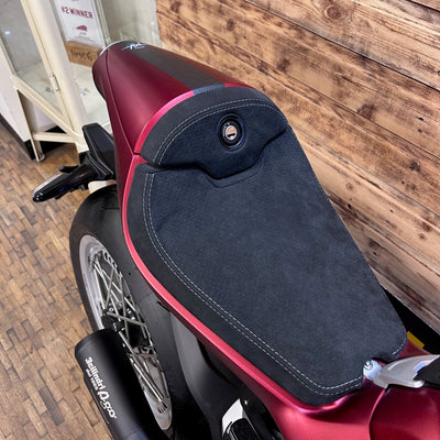 Close-up of a red and black motorcycle seat with a wooden wall background