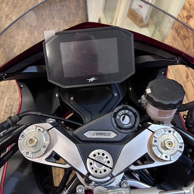 Close-up of a motorcycle dashboard with a digital display and control knobs.