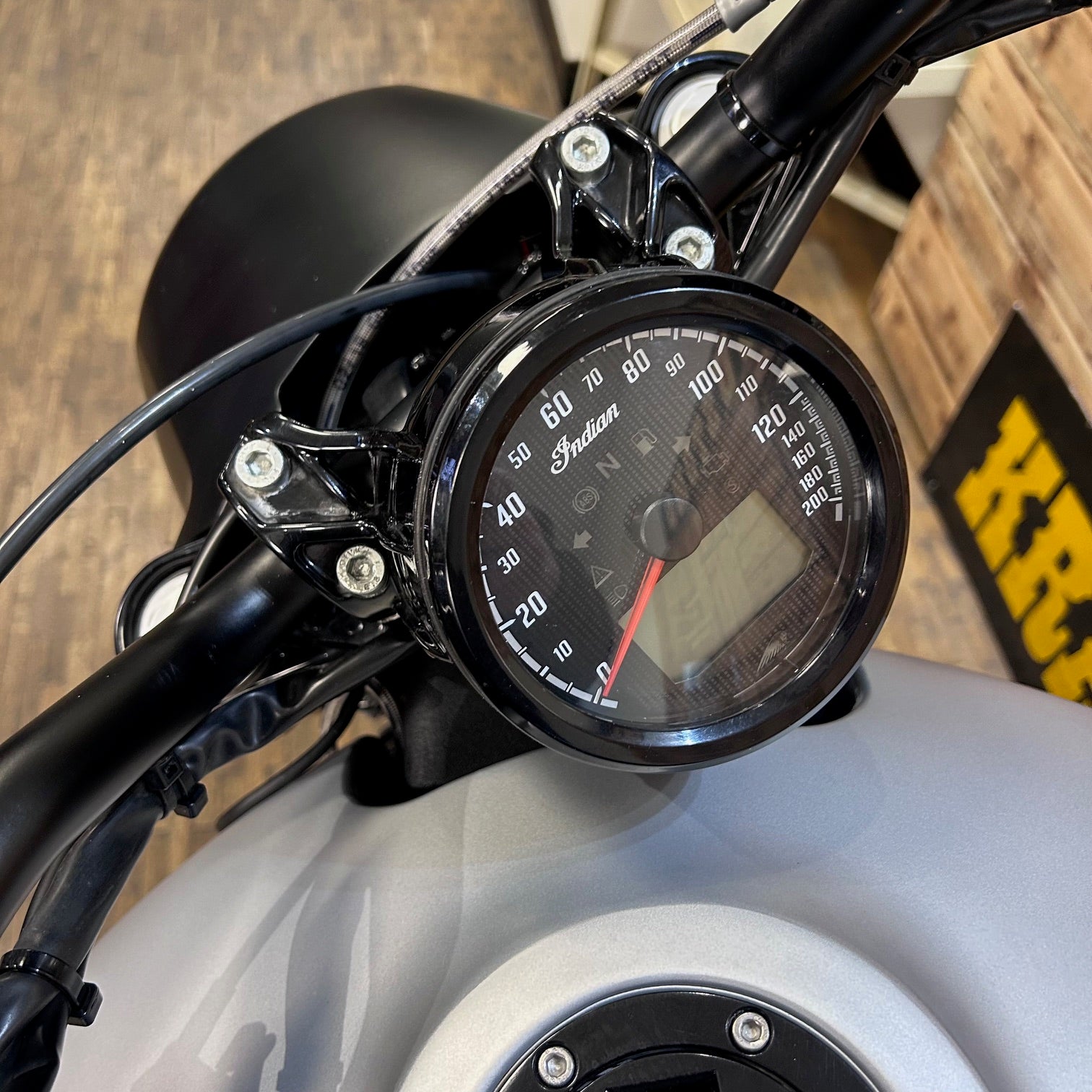 Close-up of a motorcycle gauge with a wooden background