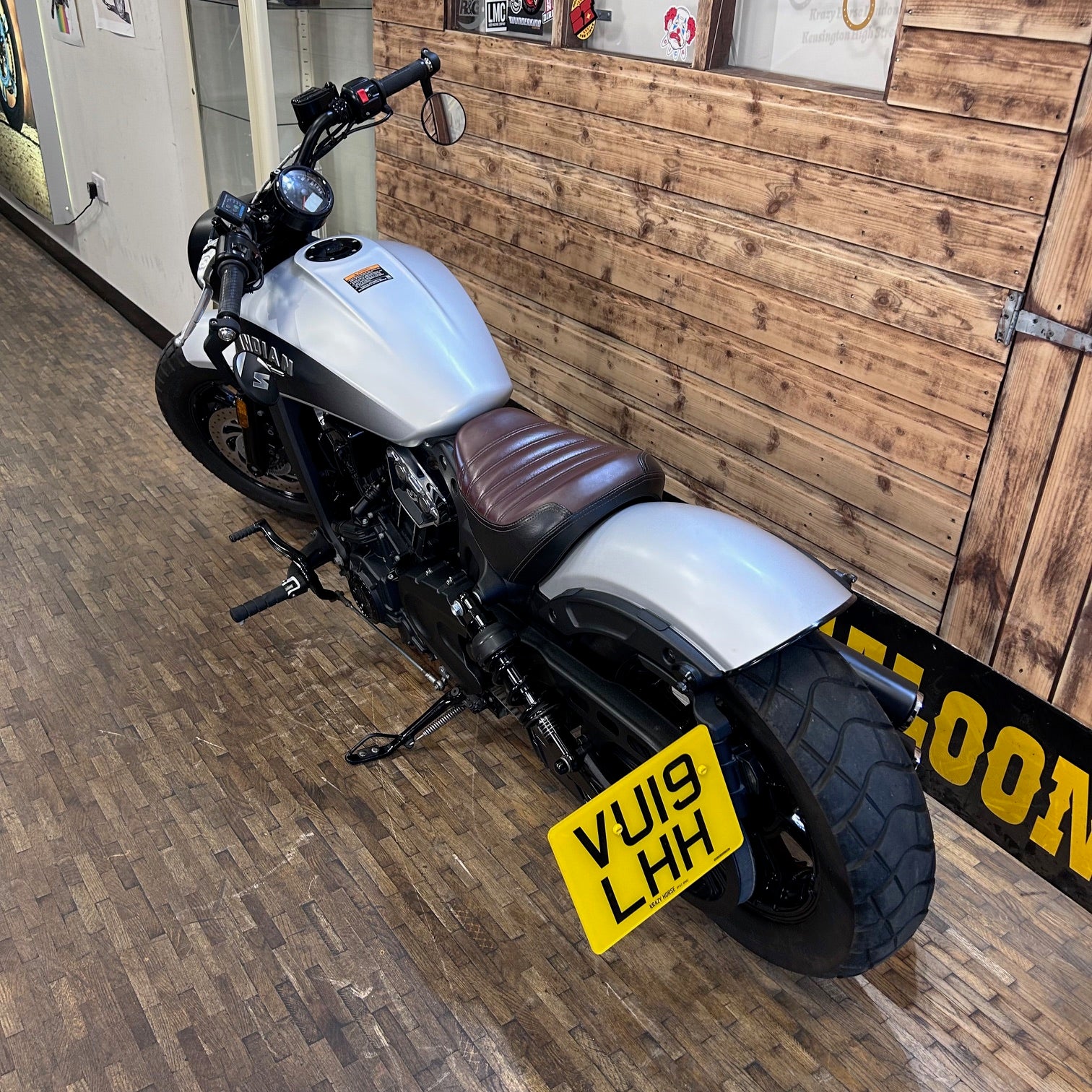 Motorcycle with a yellow license plate on a wooden floor