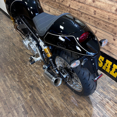 Black motorcycle on a wooden floor with a wooden wall in the background