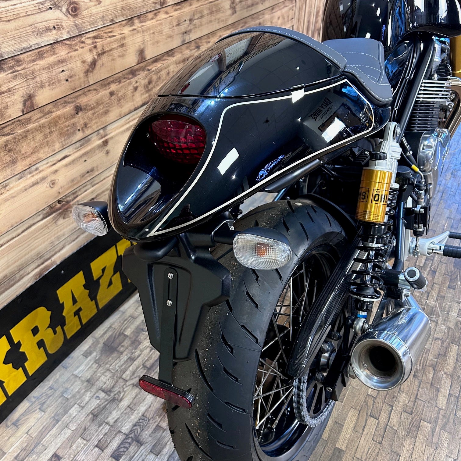 Close-up of a black motorcycle with a wooden wall background