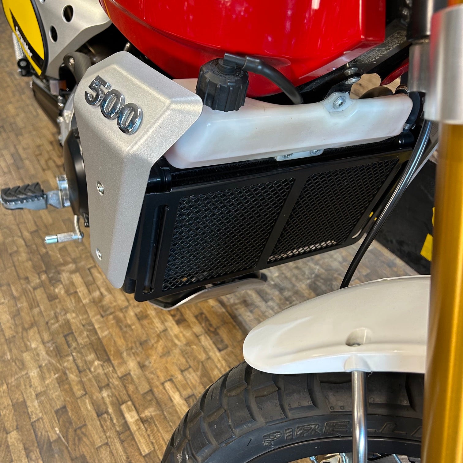 Close-up of a motorcycle radiator with '500' branding on a wooden floor.