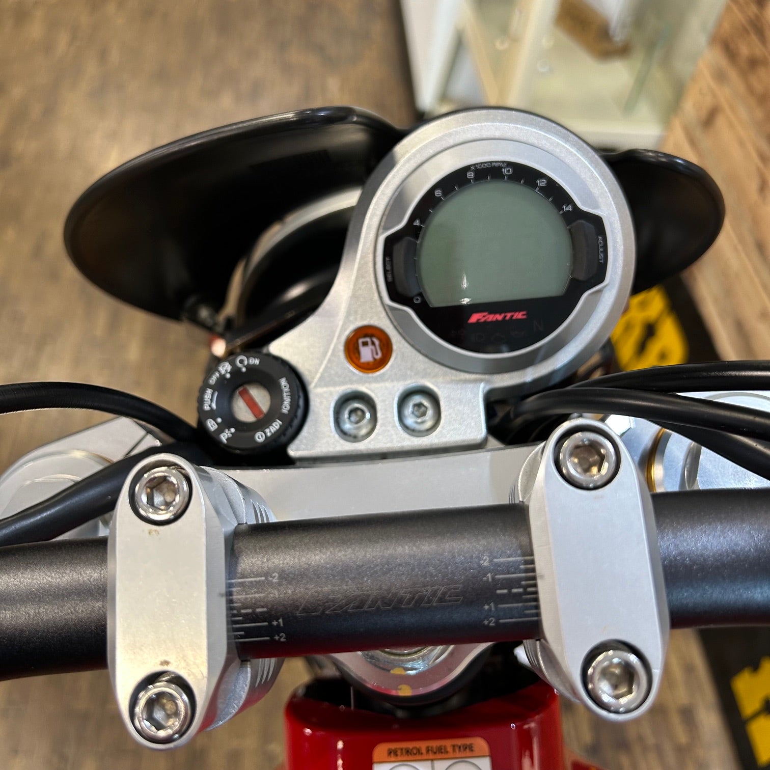 Close-up of a motorcycle handlebar with digital gauge and controls.