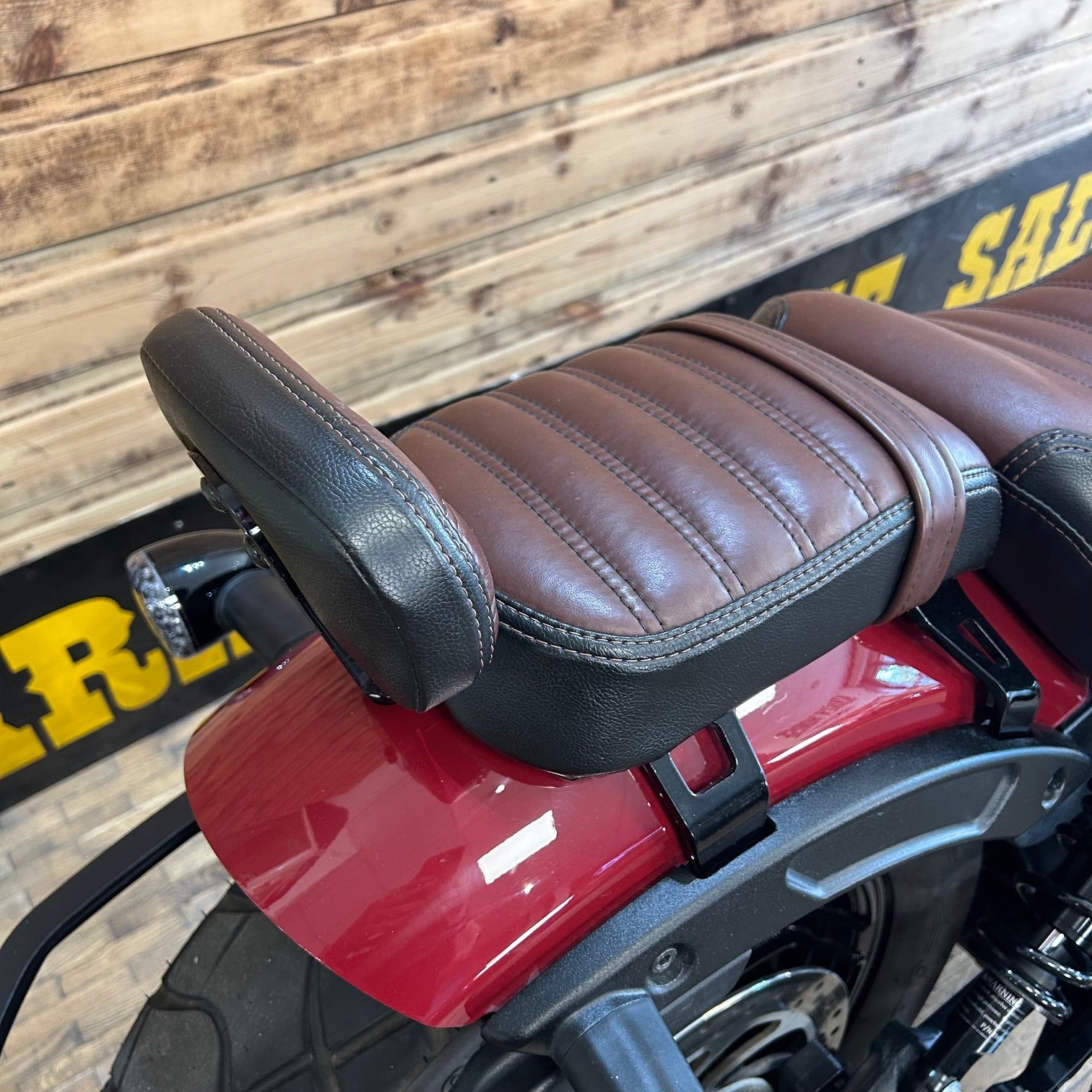 Close-up of a motorcycle seat with a wooden wall background