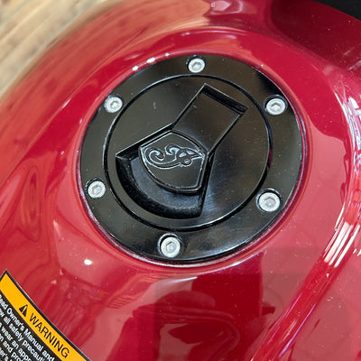 Black fuel cap on a red vehicle with a warning label.