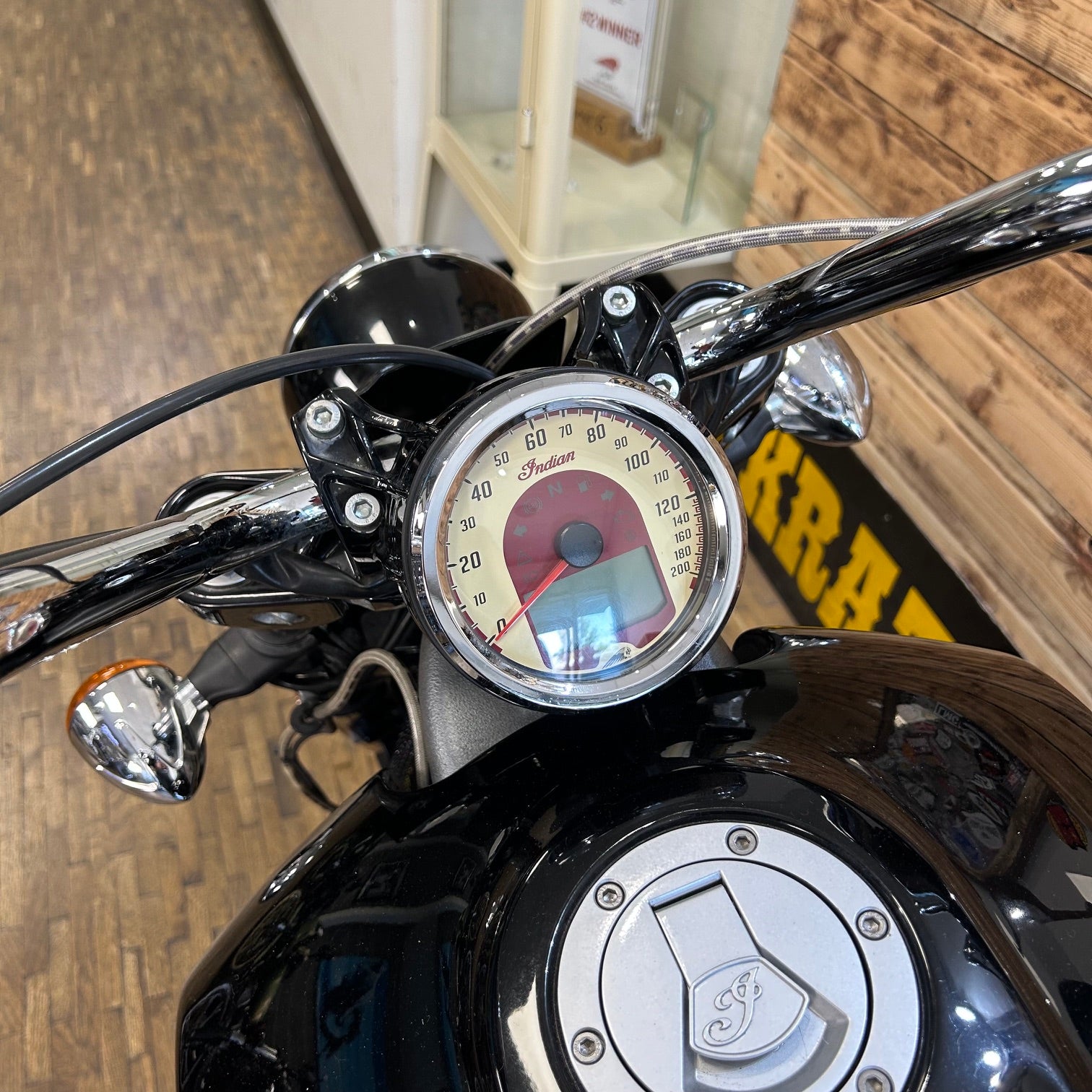 Close-up of a motorcycle's handlebar with speedometer and brand logo.