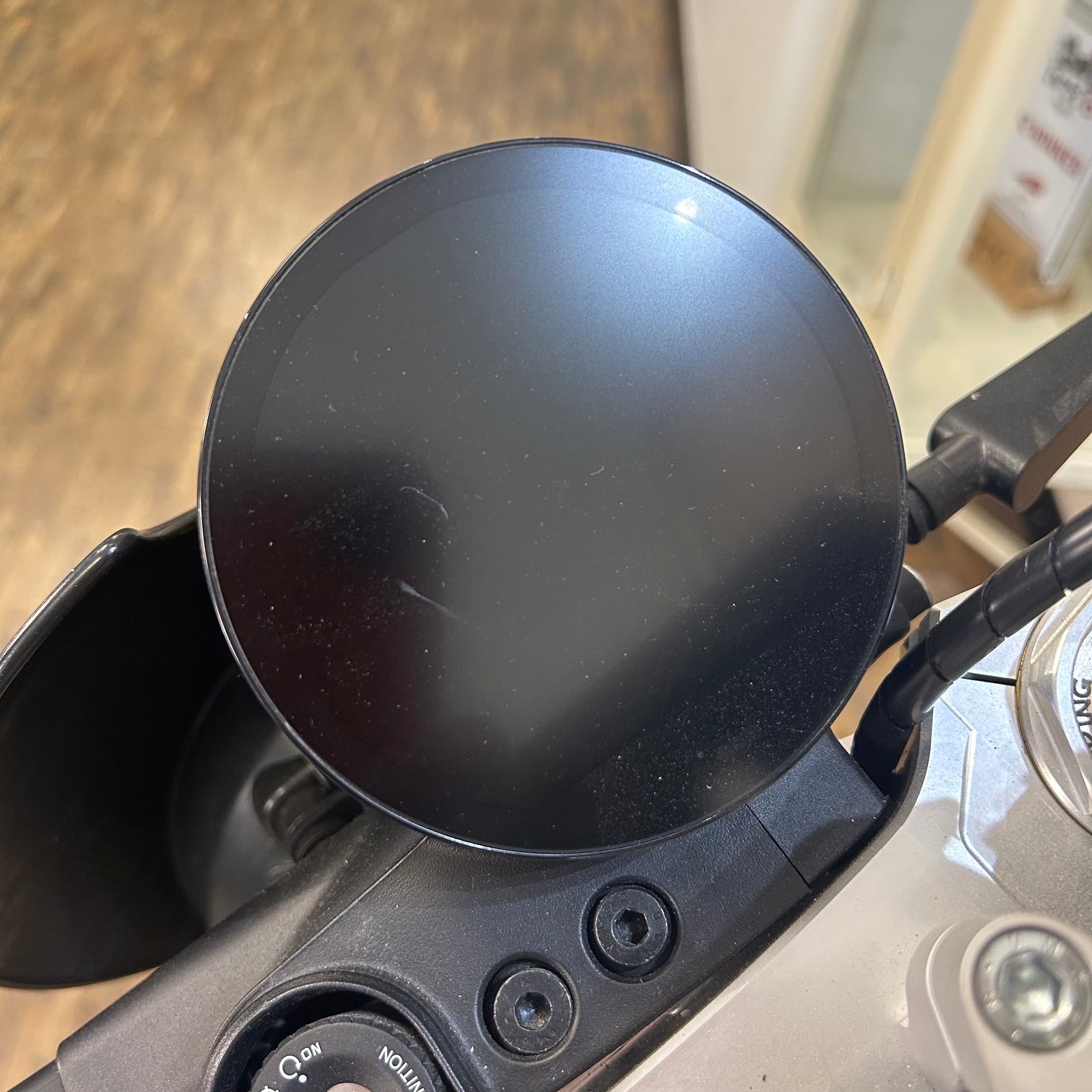Black motorcycle mirror on a handlebar with a blurred background