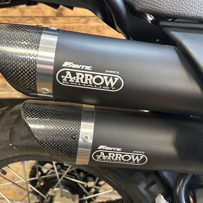 Motorcycle exhaust with 'Fantec' and 'Arrow Exhaust' branding on a blurred background.