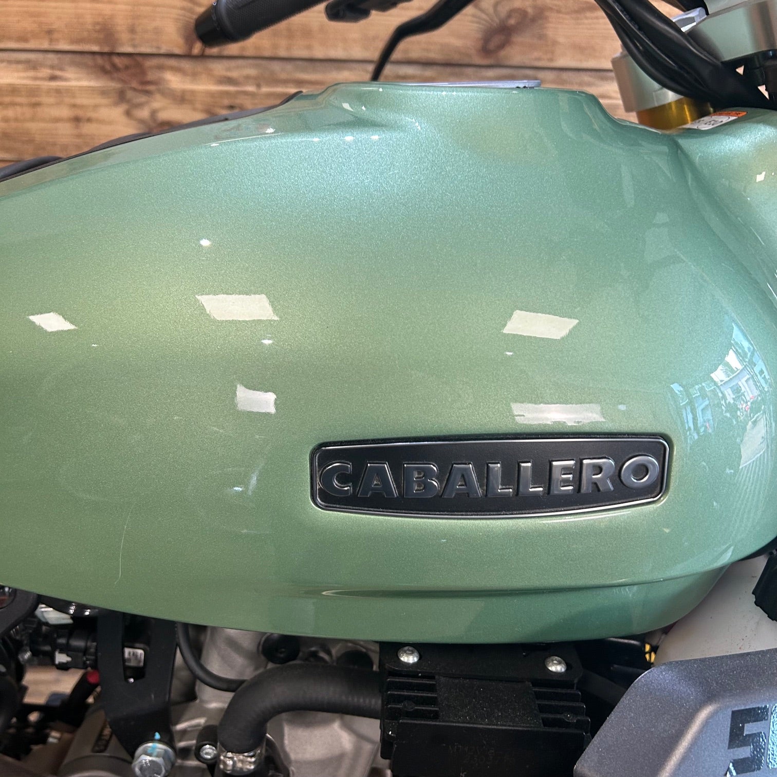Green motorcycle with 'Caballero' branding on a wooden background