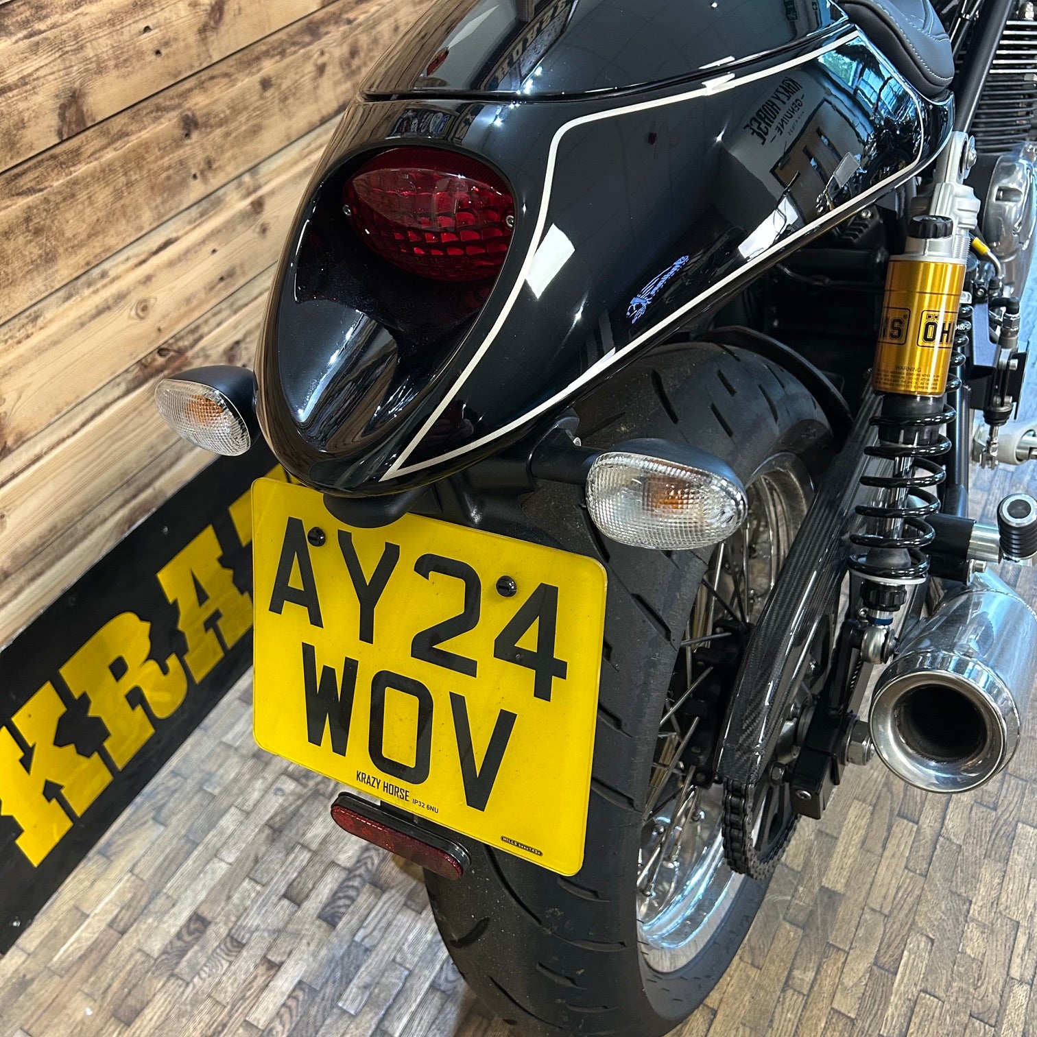 Close-up of a motorcycle with a yellow license plate against a wooden background