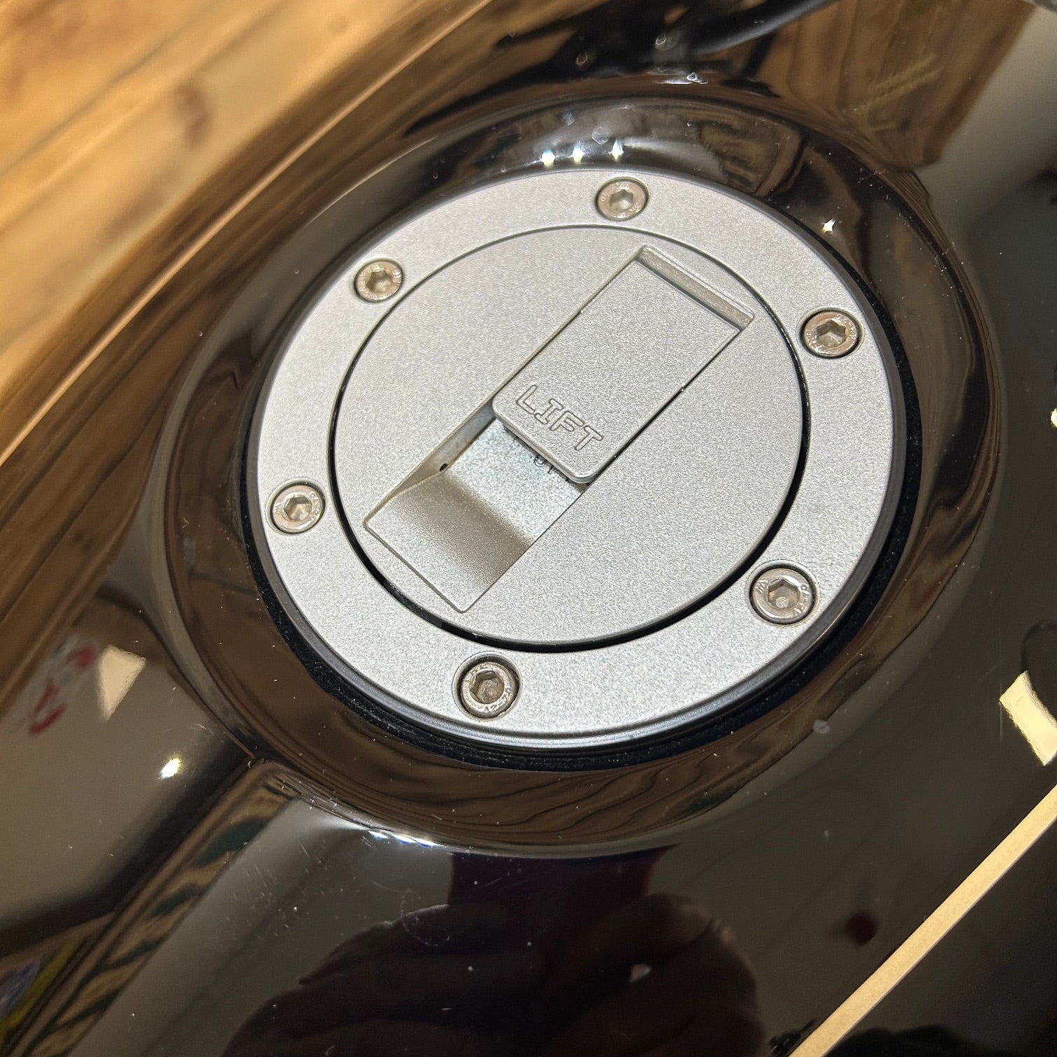 Close-up of a motorcycle fuel tank cap with 'LIFT' label.