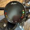 Close-up of a motorcycle instrument cluster with 'Indian' branding on a wooden surface.