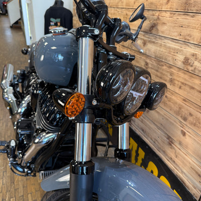 Close-up of a motorcycle's front headlight and turn signal in a showroom setting.