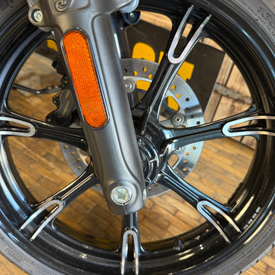 Indian - Close-up of a motorcycle wheel with an orange reflector and metallic brake components.