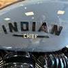 Close-up of an 'Indian Chief' motorcycle emblem on a shiny surface.