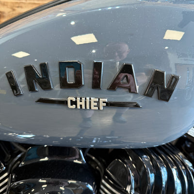 Close-up of an 'Indian Chief' motorcycle emblem on a shiny surface.