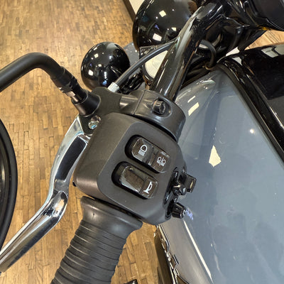 Close-up of motorcycle handlebar controls on a wooden floor background