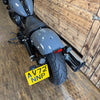 Gray motorcycle with a yellow license plate on a wooden floor.