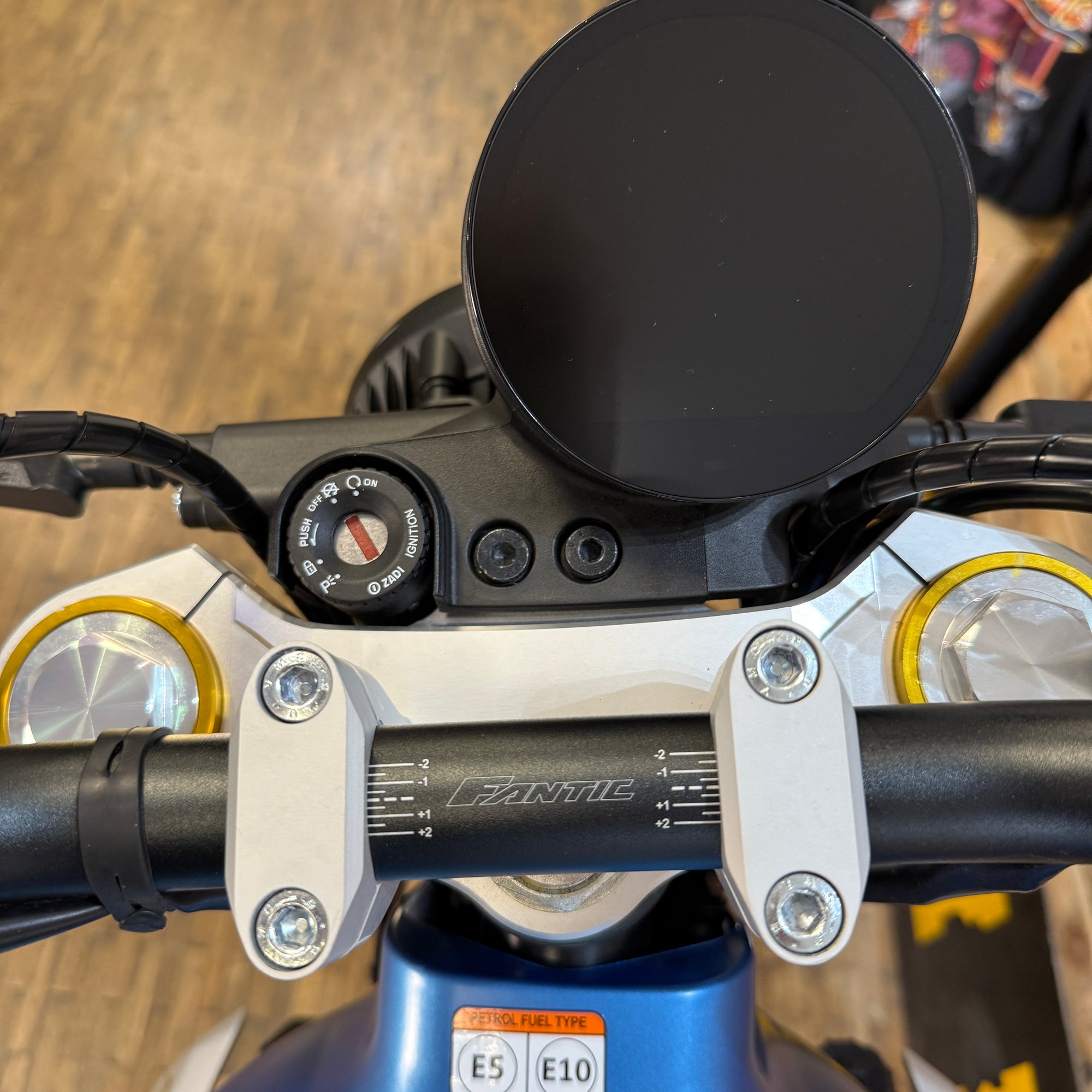 Close-up of a motorcycle handlebar with controls and mirrors on a blurred background