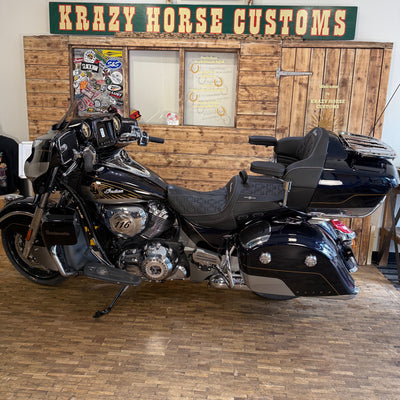 Black motorcycle in a garage with 'Krazy Horse Customs' sign in the background