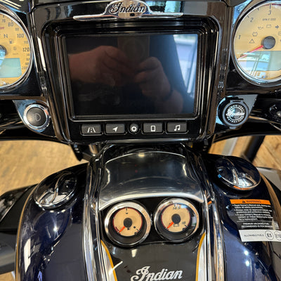 Close-up of a motorcycle dashboard with digital display and gauges, featuring the 'Indian' brand.