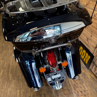 Close-up of a black motorcycle with chrome details on a wooden floor.