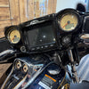 Close-up of a motorcycle dashboard with an 'Indian' logo, featuring two round gauges and a screen.