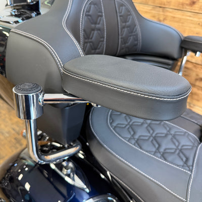 Close-up of a motorcycle seat with armrest and chrome handlebar