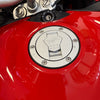 Close-up of a red motorcycle fuel tank with a silver cap featuring branding.
