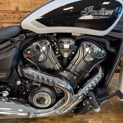 Close-up of a motorcycle engine with 'Indian Scout' branding on a wooden floor.