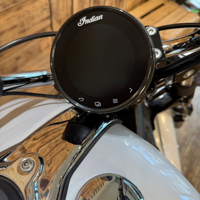 Motorcycle handlebar with an 'Indian' branded control panel on a wooden surface.