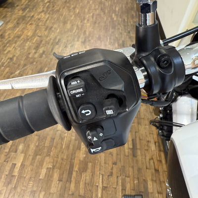 Close-up of motorcycle handlebar controls with a wooden floor background