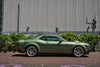 Green sports car parked in front of a metallic building with greenery.