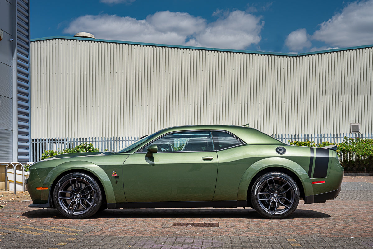 Green sports car parked in front of a building with a blue sky.