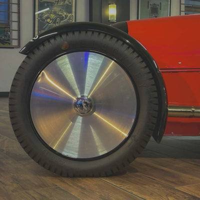 Close-up of a car wheel with a shiny hubcap in a showroom setting