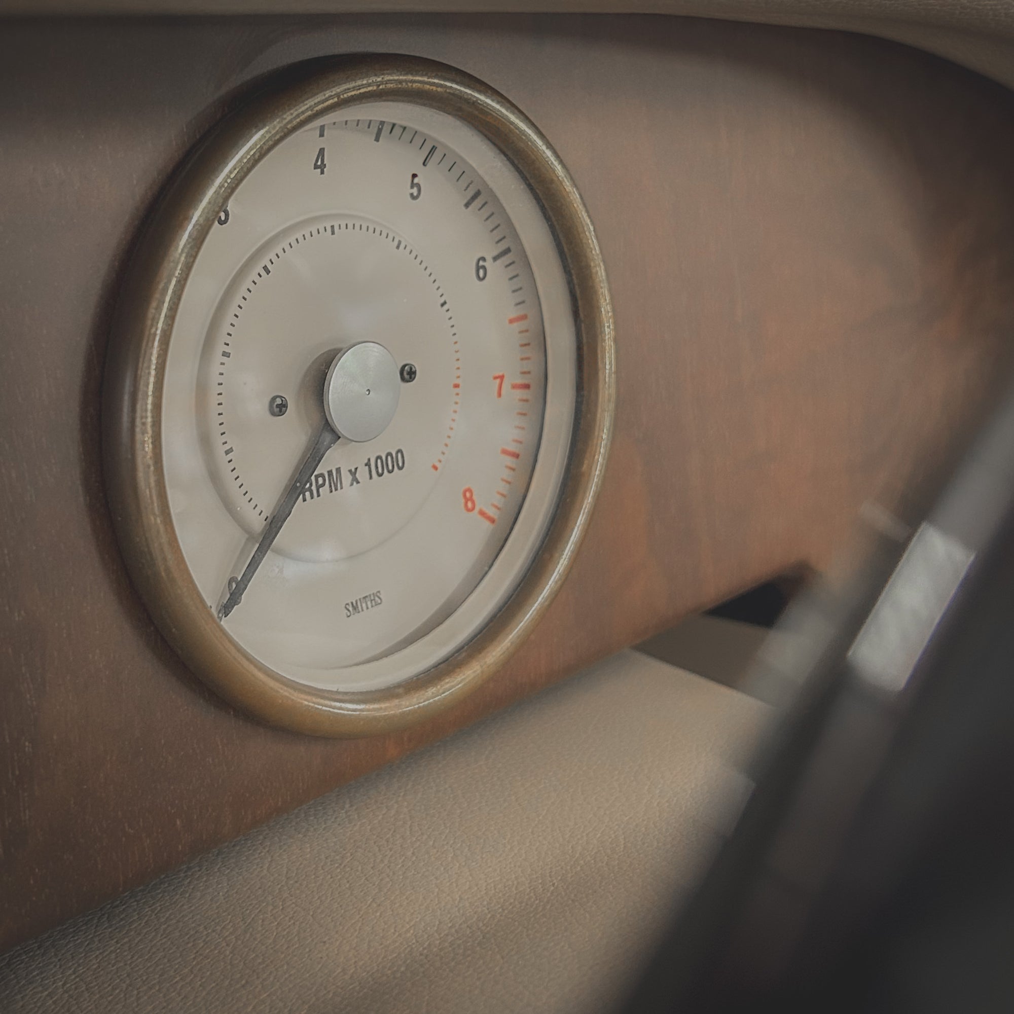 Close-up of a vintage car dashboard with an RPM gauge.