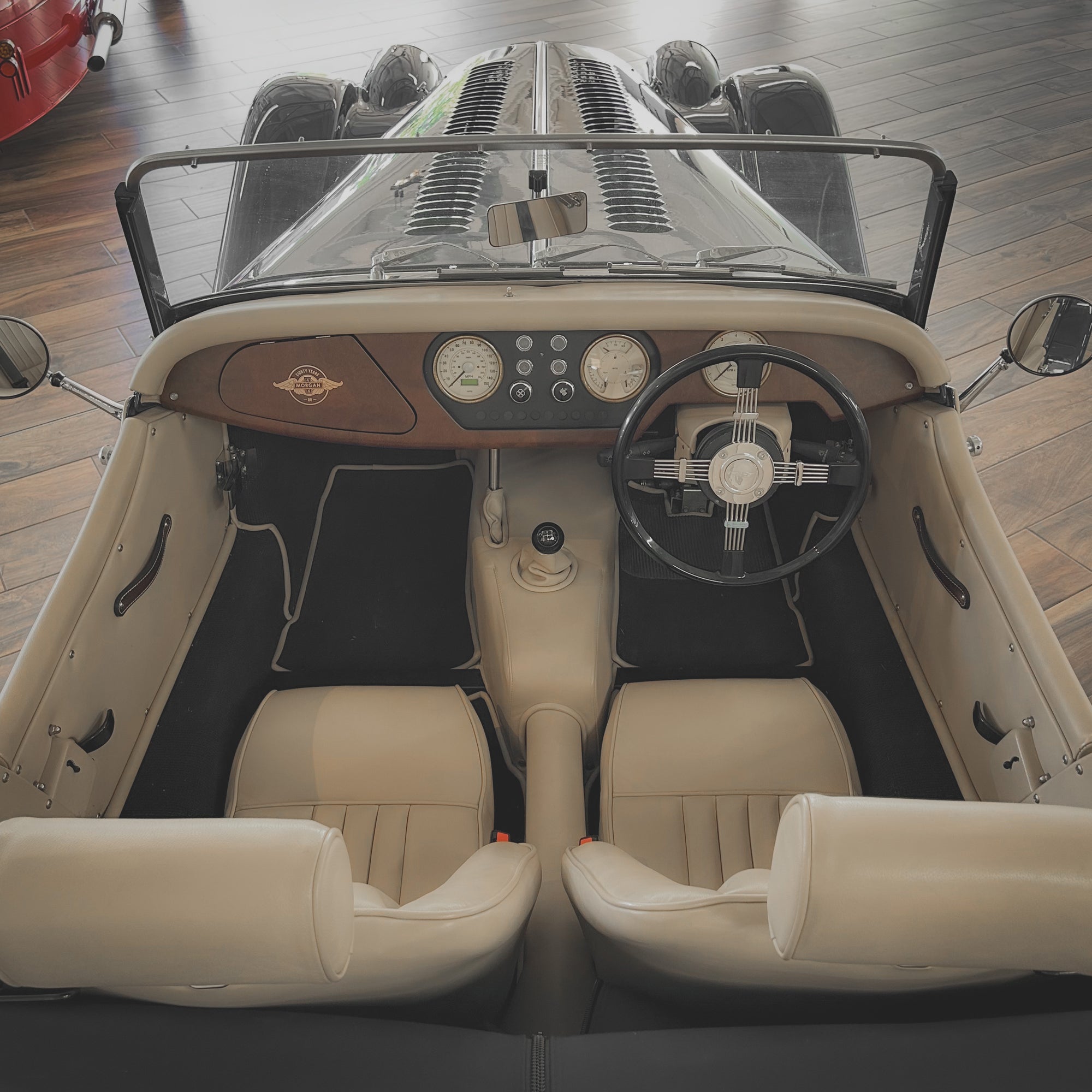Vintage car interior with beige leather seats and wooden dashboard.