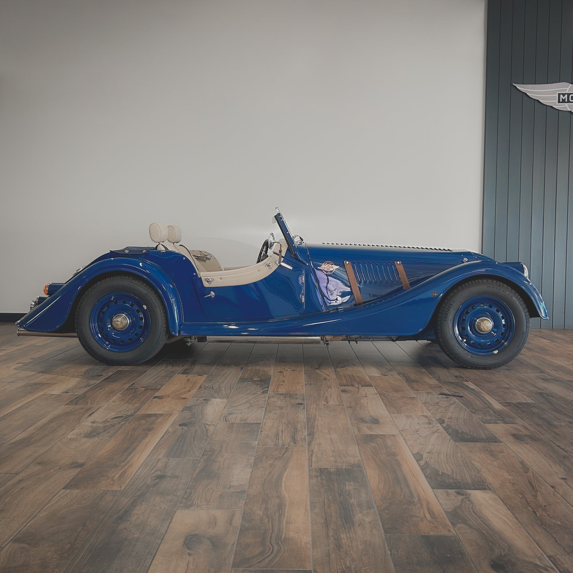 Blue vintage car on a wooden floor with a neutral background