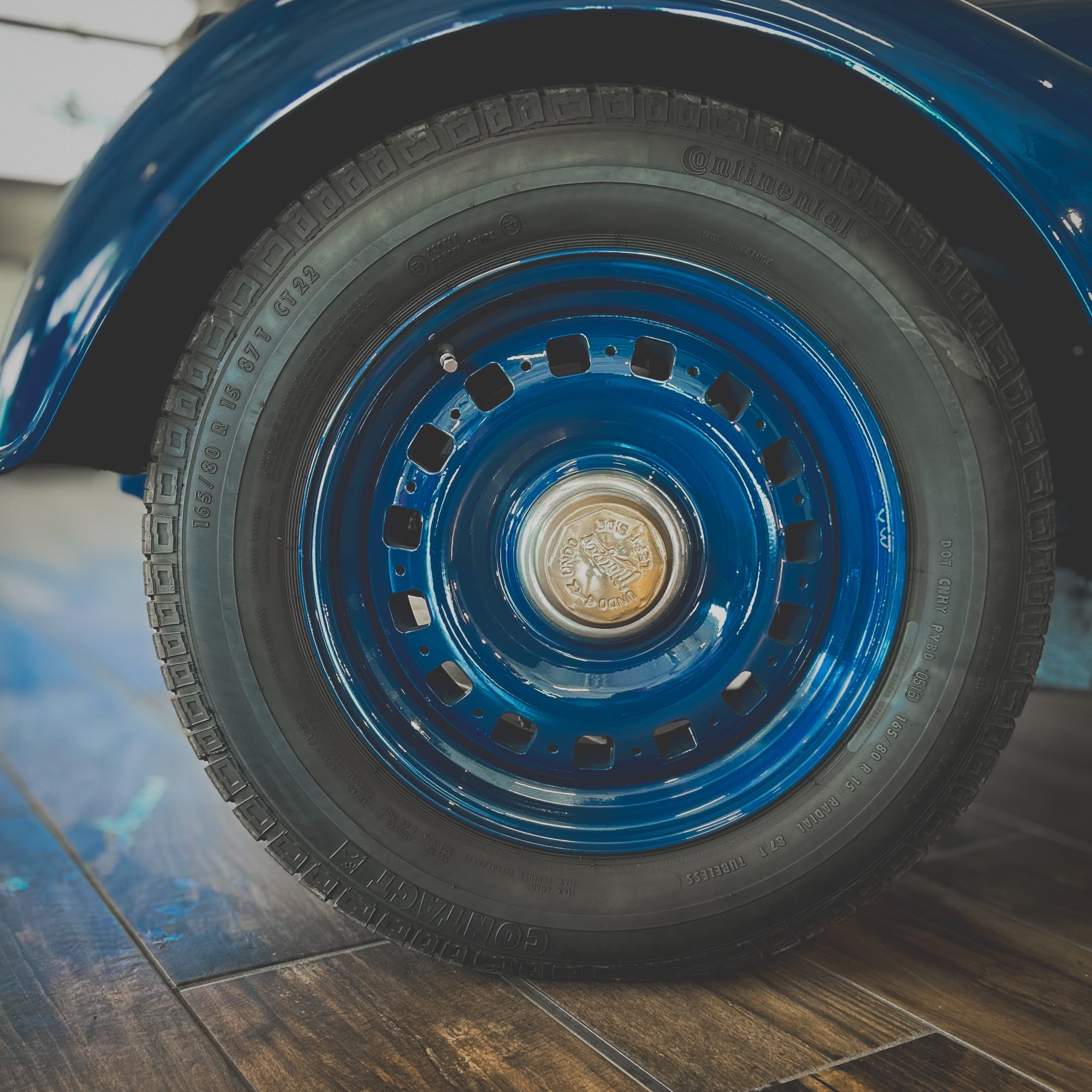 Close-up of a blue car wheel with a wooden floor background
