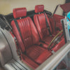 Red leather interior of a classic car with a steering wheel.