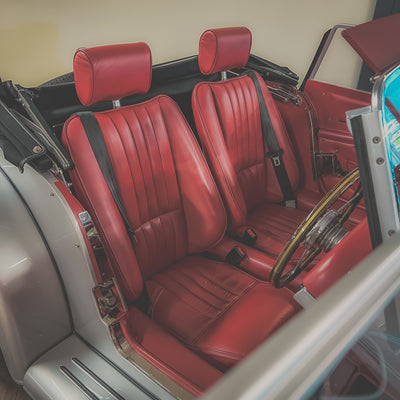 Red leather interior of a classic car with a steering wheel.