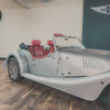 Vintage car with red interior on a wooden floor, MORG logo in the background
