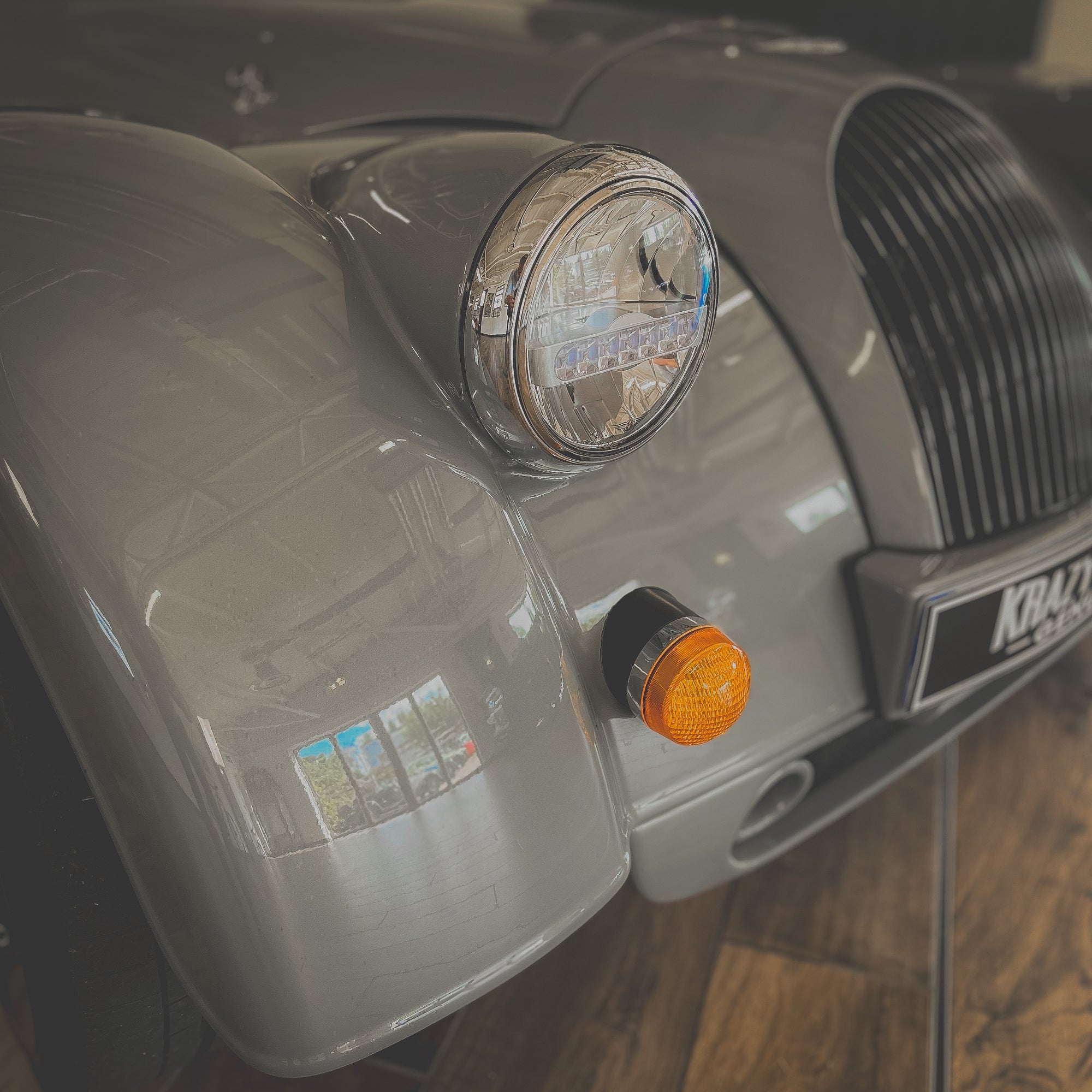 Close-up of a vintage car's front headlight and grille with 'Kraft' branding.