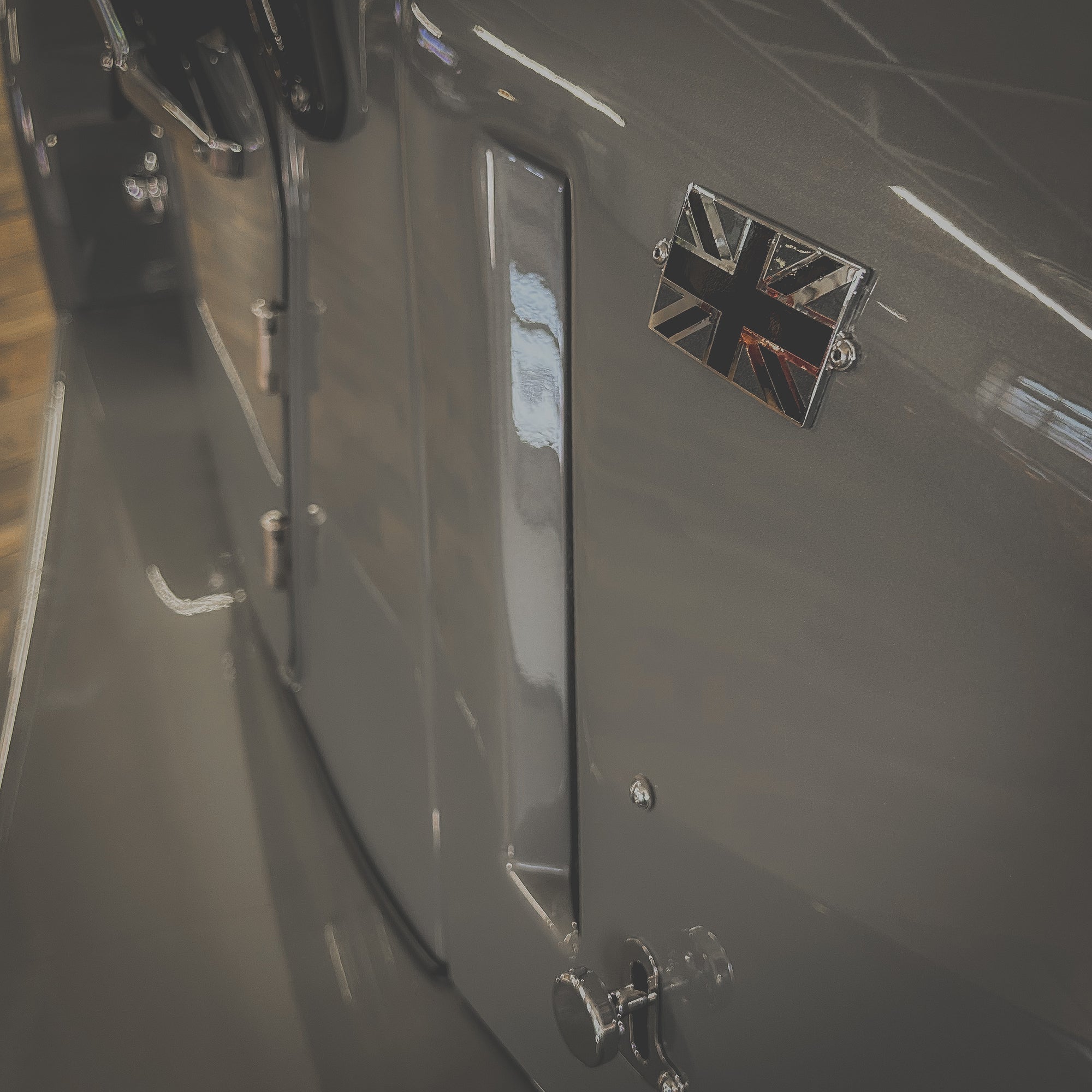 Close-up of a car door with a British flag emblem on a blurred background