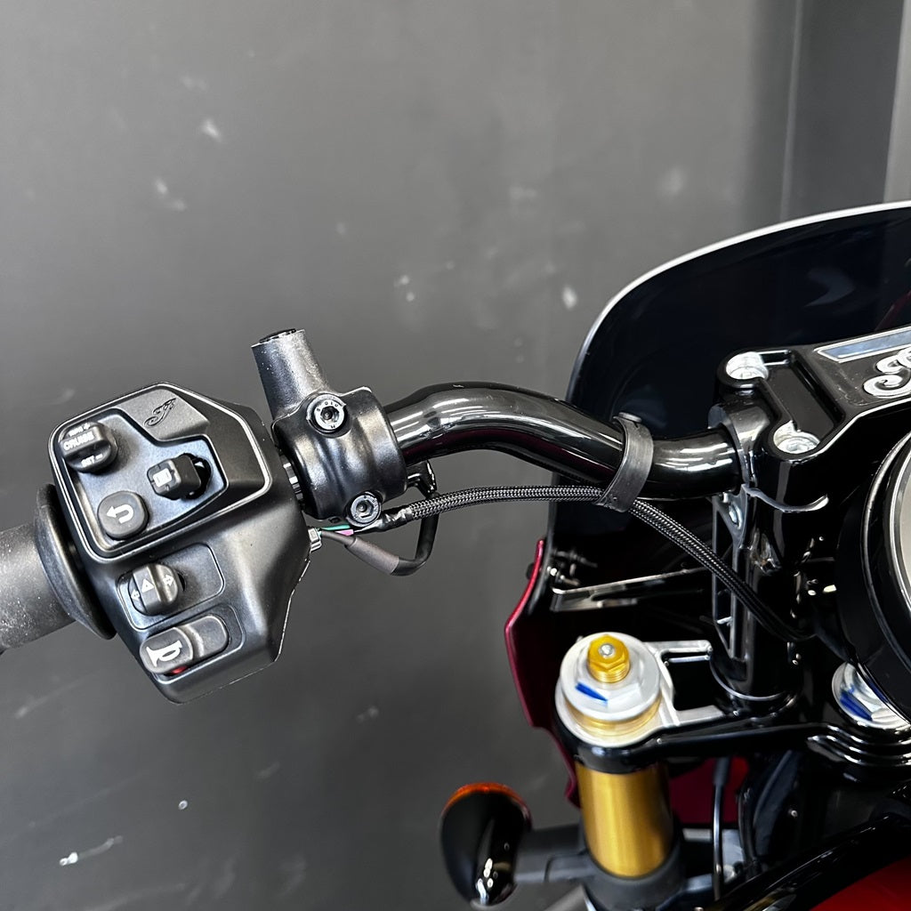 Close-up of a motorcycle handlebar with control buttons and throttle grip.