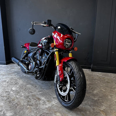 Red motorcycle parked against a black wall on a concrete floor