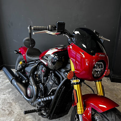 Red motorcycle with gold front forks on a gray floor against a black wall